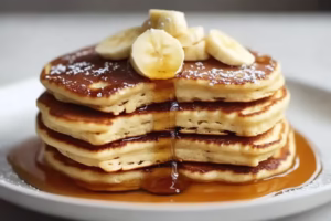 Fluffy vegan pancakes topped with fresh berries and maple syrup